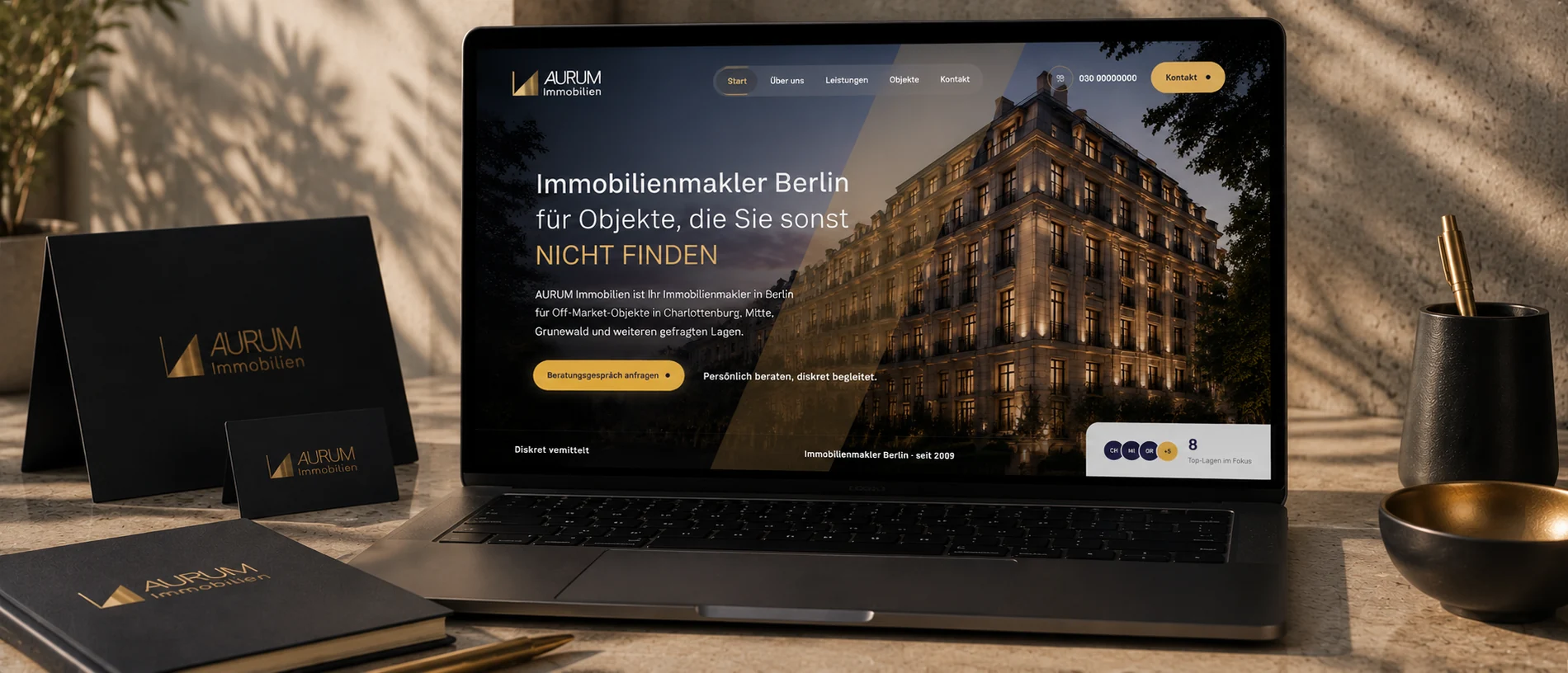 AURUM Markenauftritt: die Website auf einem Laptop, daneben Visitenkarten und eine dunkelblaue Mappe mit Goldprägung